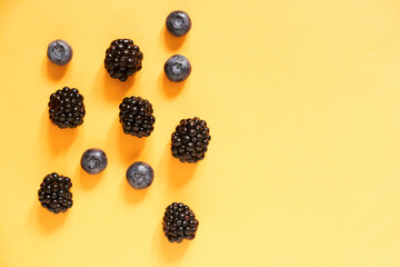 Blackberries and blueberries on an illuminating yellow background with copy space. High quality photo
