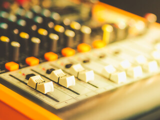 White mic channel volume button That pushed up a little On an orange sound mixer There are many buttons, colorful light.
