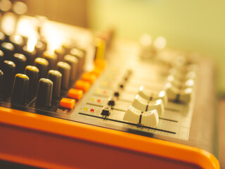 White mic channel volume button That pushed up a little On an orange sound mixer There are many buttons, colorful light.