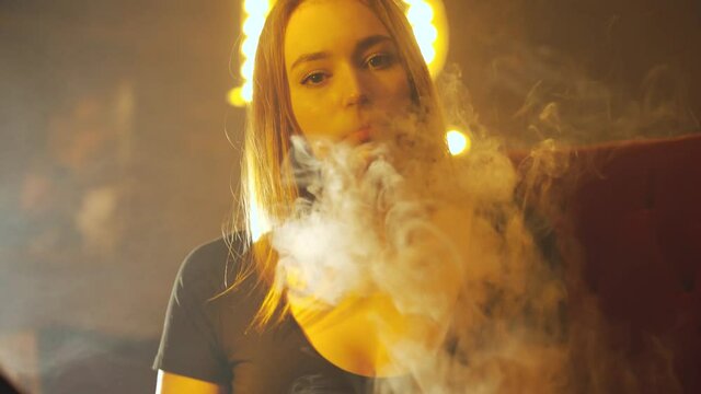 A girl smokes a hookah in a nightclub