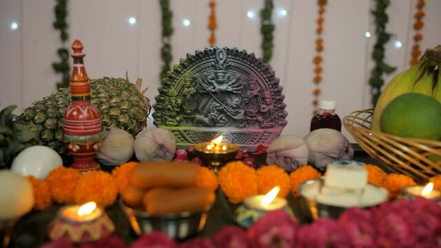 Closeup shot of a colorful temple/puja Ghar decorated on Durga Puja festival. Beautifully decorated platform with Ma Durga's idol surrounded by burning Diyas  sweets  fruits  and flowers