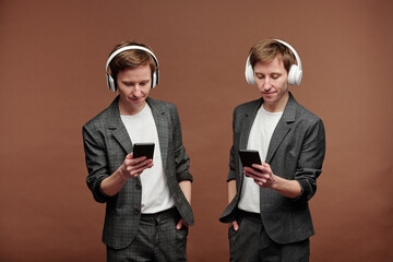 Twins in suits enjoying music in headphones