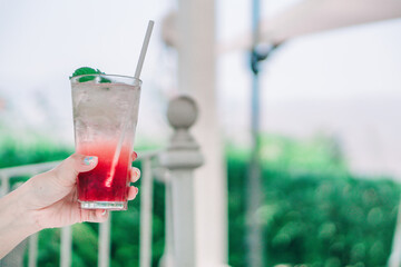 Red Soda Water in Hand with Tree Backdrop