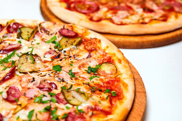 Pizza with salami, bell pepper, tomatoes and cheese, pickles, bacon and sausages on a light background. Close-up, selective focus