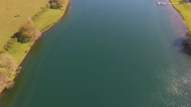 4K flying over hawkridge reservoir, drone moving forward over the water revealing the fishing boats docks and the water dam wall, 60fps.