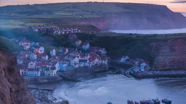 Staithes Harbour and Village Timelapse from headland with mist through to dusk with village lights illuminating, atmospheric