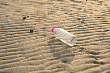 plastic bottle lies on the sand