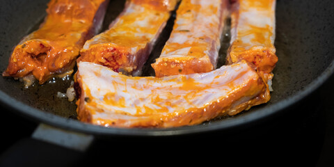 Pork ribs meat close-up in a frying pan