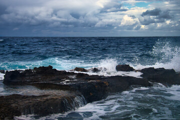 Ocean water splashing over rocks on a stormy day in Qawra, Malta.