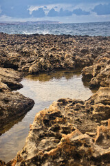 Pool of water on a beach in Qawra, Malta on a cloudy day.