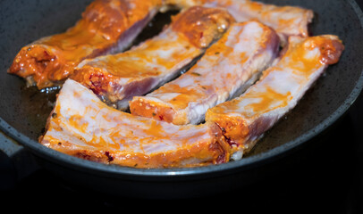 Pork ribs meat close-up in a frying pan