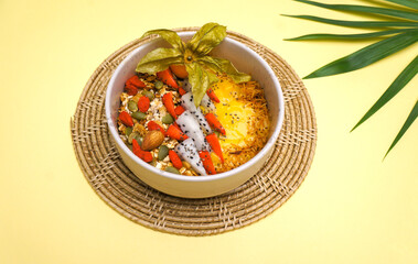 Eating healthy breakfast bowl. pineapple, mango smoothie, granola, seeds, strawberries in White ceramic bowl in female hands.detox, vegetarian, vegan food concept