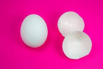 White egg and  eggshell on the pink background. Copy space. Minimalism, original and creative photo. Beautiful wallpaper. Easter holidays.