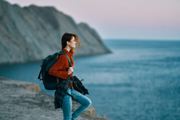 woman with backpack on her back red sweater jeans hiking mountains ocean