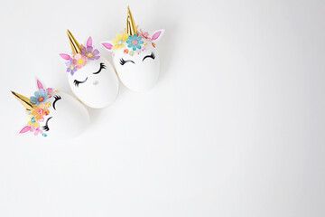 Fototapeta na wymiar Three Easter eggs decorated with unicorn stickers on a white background. Copy space. Top view. Background for Easter.