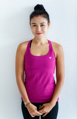 Fototapeta na wymiar Portrait of Asian beautiful energetic healthy sportive woman with hair tied wearing pink or purple tank top, standing on white background.