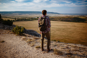 man hiking in the mountains using pole and looking away