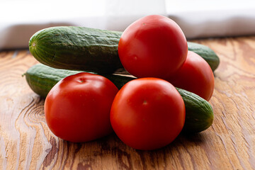 two cucumbers and four tomatoes on a wooden background