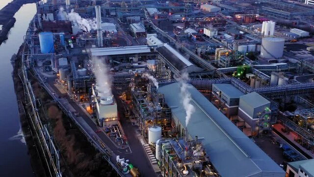 Large chemical plant drone shot after sun set in UK. Steam coming from cooling towers and plant lights on.