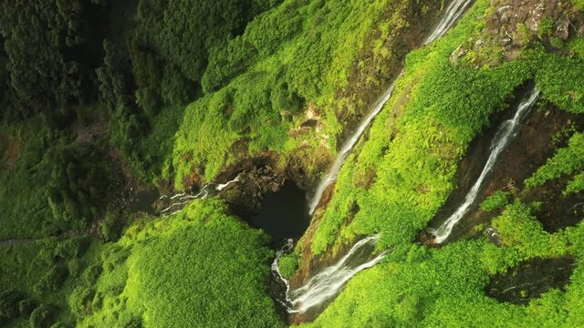 Overhead view of natural waterfalls in Poco Ribeira do Ferreiro, Alagoinha valley, Flores Island, Azores, Portugal, Europe. Aerial view of waterfalls surrounded green vegetation, 4k footage