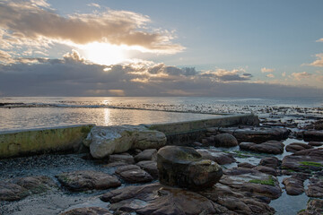Sunrise over seawall jetty at Dale Brook Tide Pool in Cape Town South Africa RSA