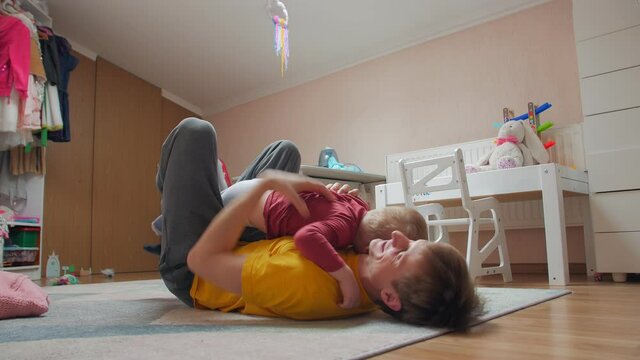 Man fooling with son lying on the floor home in quarantine