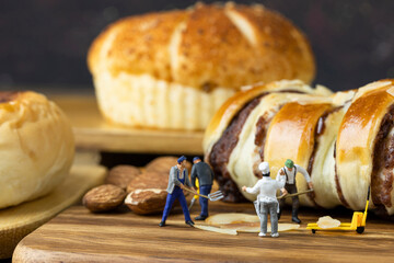 Miniature Chef is urging the miniature workers to make bread on wooden tray.
