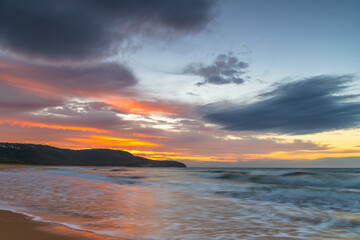 Naklejka na ściany i meble Sunrise at the seaside with pastel coloured clouds