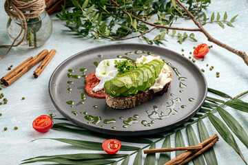 Appetizing avocado sandwich with tomato and poached egg for breakfast
