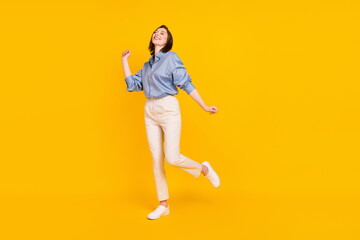 Photo of pretty adorable young woman wear blue shirt smiling dancing isolated yellow color background
