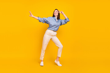 Fototapeta na wymiar Photo of funny cute young lady dressed blue outfit showing v-signs dancing isolated yellow color background