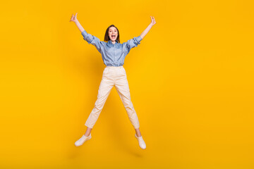 Fototapeta na wymiar Photo of pretty funky young woman wear blue shirt smiling jumping high like star empty space isolated yellow color background