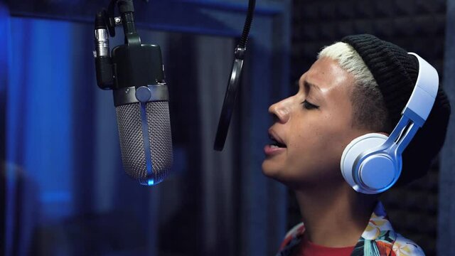 Young woman singer recording a new song album inside music production studio