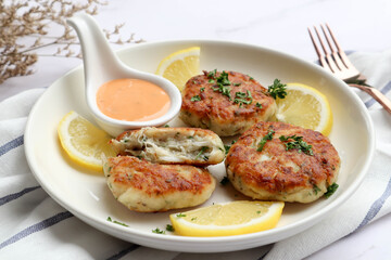 Crab cake with remoulade sauce and lemon in a white plate at close up view - healthy seafood appetizer