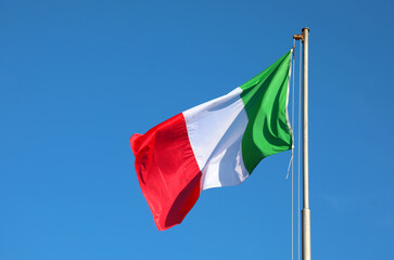 Italian flag waving with bright colors and the blue sky in the background
