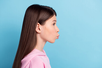 Photo of flirty charming school girl wear pink sweatshirt sending kiss empty space isolated blue...