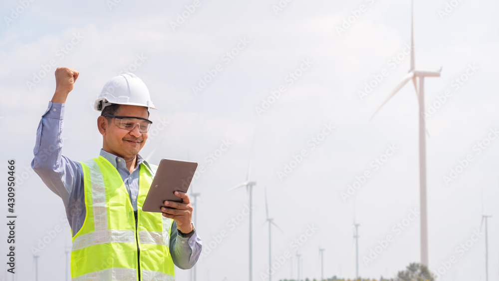 Wall mural successful engineer windmills using tablet with wind turbine in background