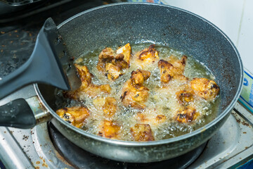Fried pork bones in a pan on the gas stove in the kitchen