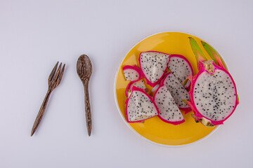 Dragon fruit on plate and spoon wooden fork on white background