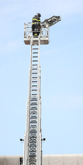 Fototapeta na wymiar basket of the ladder truck with the fire brigade during the rescue maneuver