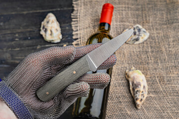 Hand with oyster knife in protective gloves. Close up. 