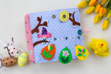 Fototapeta na wymiar Handmade textile book for baby. Easter present for baby. Pages with felt eggs, birds and rabbits. Woolly toys on a string. Baby development. Educational toys. Fine motor skills.