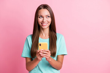 Photo of young young beautiful dreamy smiling cheerful woman using smartphone look copyspace isolated on pink color background