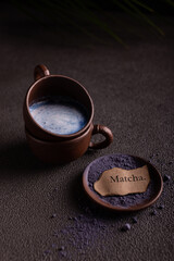 Cups of blue matcha tea with milk and powdered tea on the table