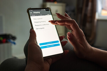 Male thumb finger over parcel delivery app on smartphone screen