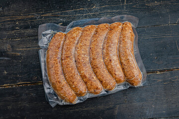 Vacuum-packed meat sausages on a wooden background.