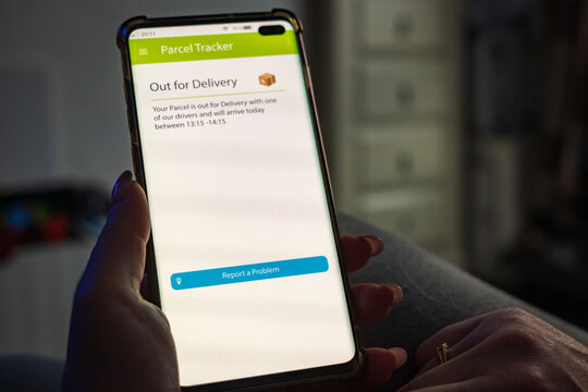Male thumb finger over parcel delivery app on smartphone screen