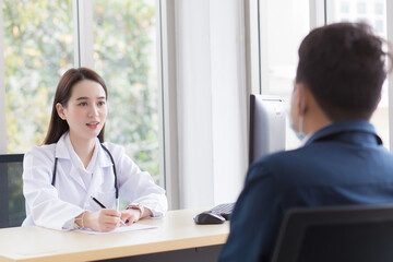 Obraz premium Asian professional woman doctor who wears medical coat talks with a man patient to consult and suggest healthcare information to him.