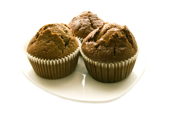 Three gingerbread muffins in cups on a plate.