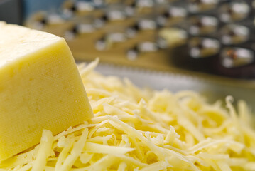 Cheese and grated cheese on a metal grater, close-up. blurred background